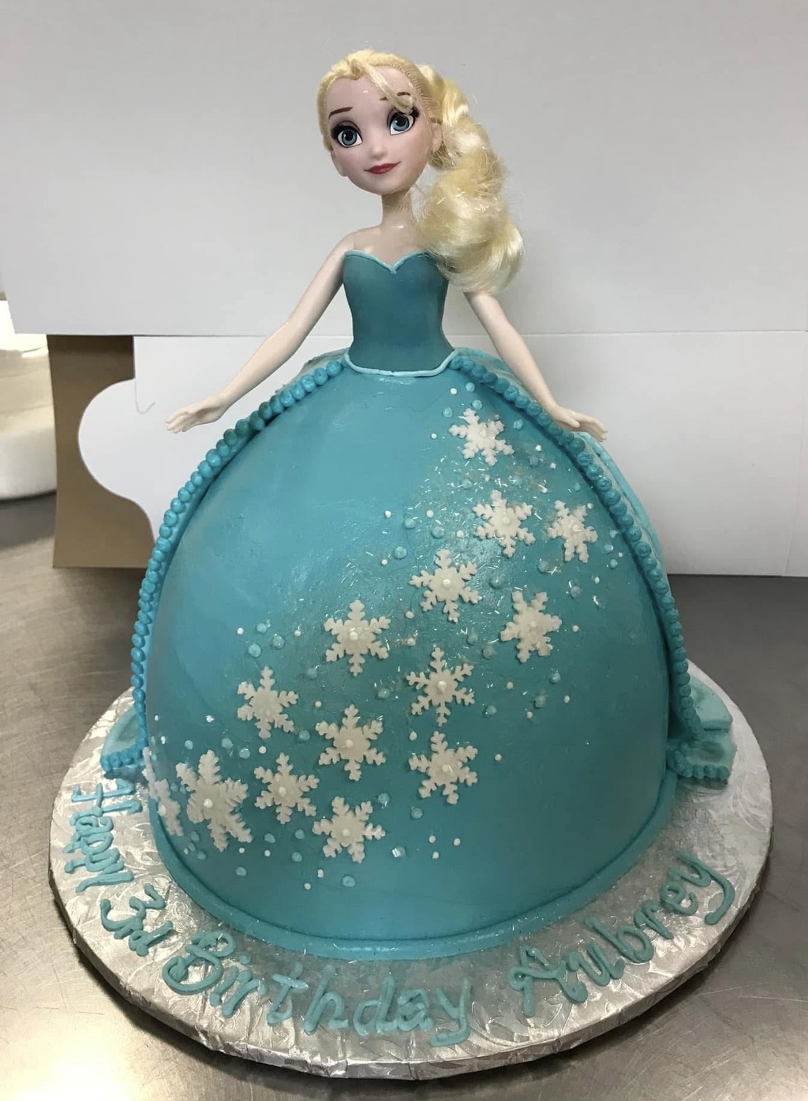 Frozen Elsa doll cake with a snowflake-covered ice-blue buttercream gown
