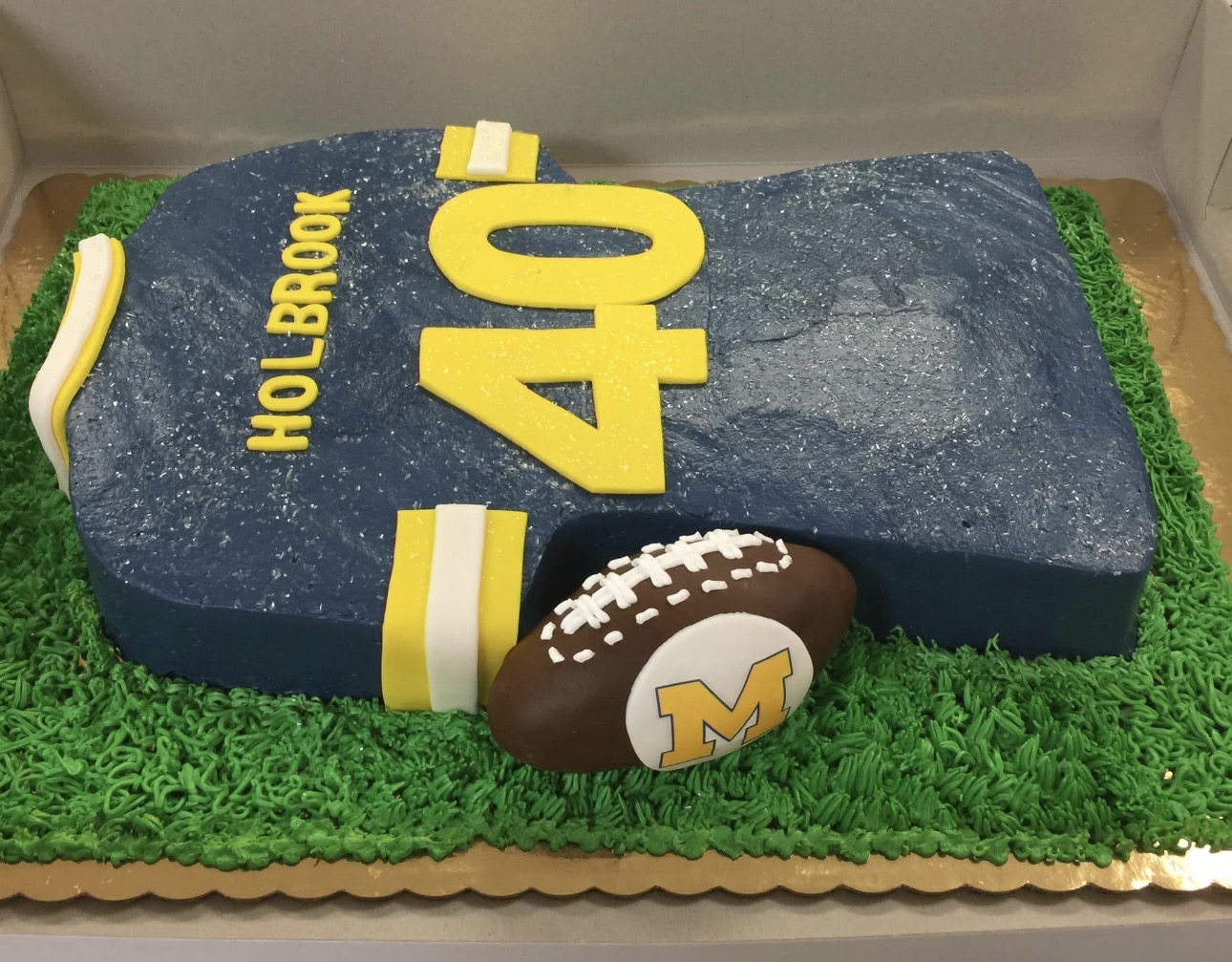 Michigan Wolverines football jersey 40th birthday cake with fondant football on green buttercream grass