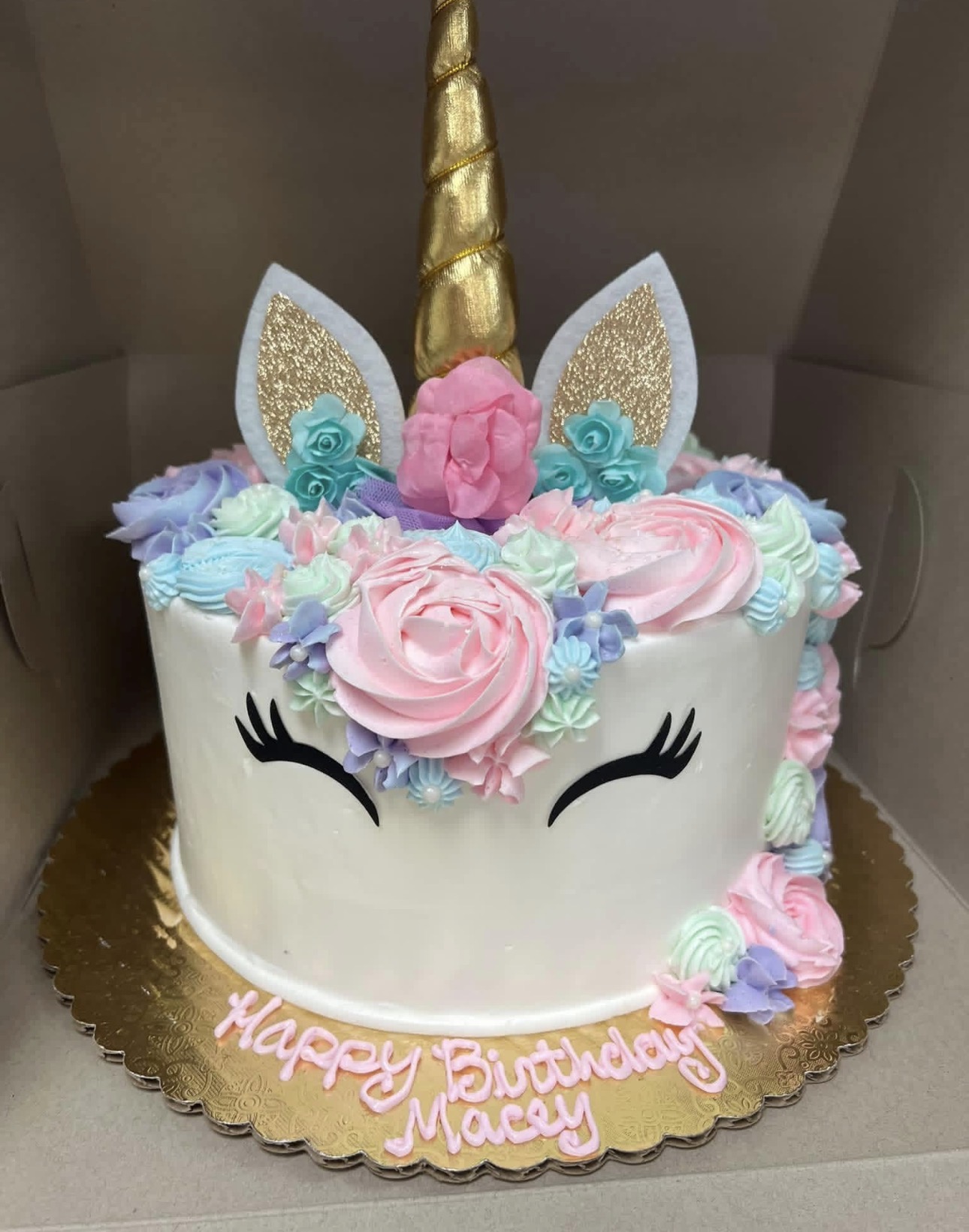 Unicorn birthday cake with gold horn, pastel buttercream rosettes and 'Happy Birthday Macey' in pink