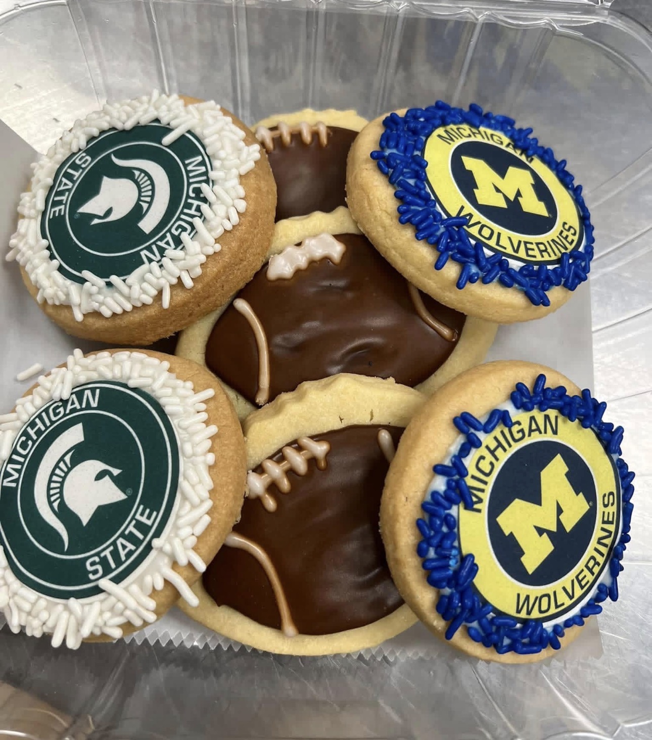 Michigan State and Michigan Wolverines logo sugar cookies with sprinkle borders and chocolate footballs