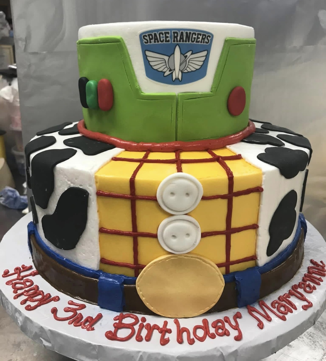 Two-tier Toy Story cake with Buzz Lightyear top tier and Woody cowboy shirt bottom tier
